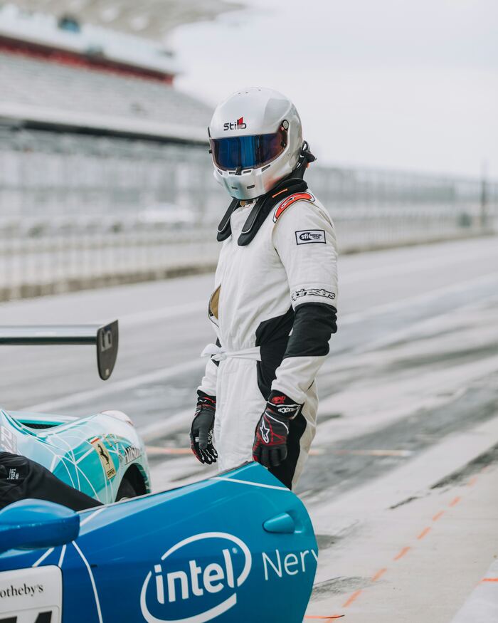 Driver in race suit beside a GT race car