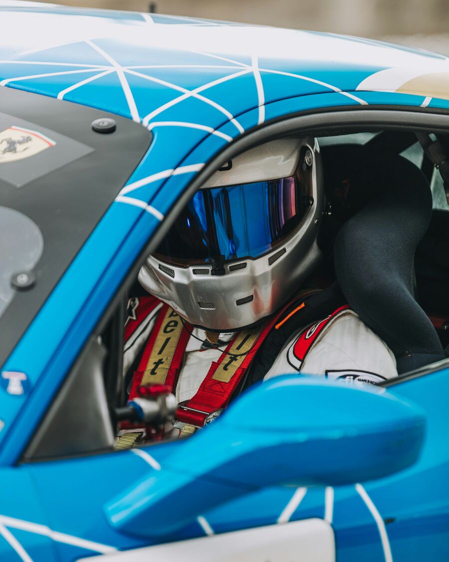 Driver in the cockpit of a blue GT car
